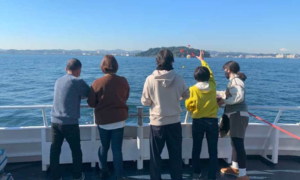 横須賀・猿島沖での海洋散骨の様子。ご家族が花を手向け、穏やかな海に見送っている場面