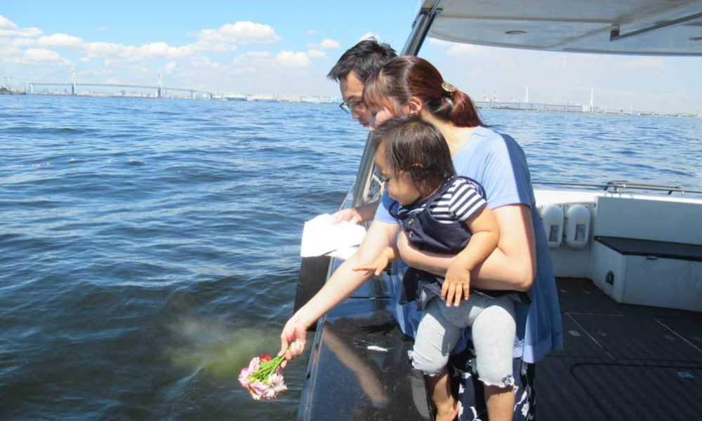 横浜・ベイブリッジ沖で家族が合同散骨を見送り、花びらを海へ手向ける