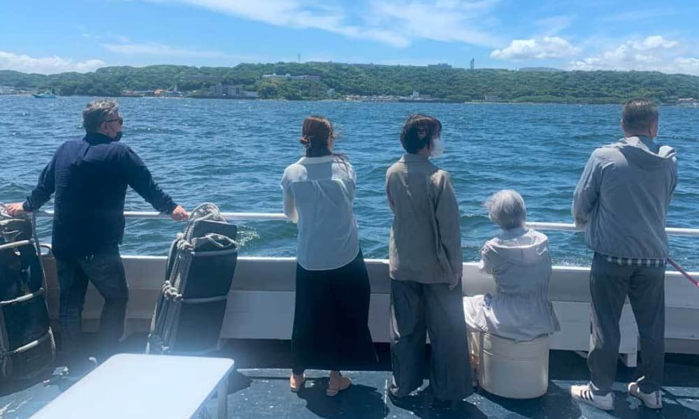横須賀基地沖での海洋散骨後、ご家族が海を見つめ静かに故人を偲んでいる様子。穏やかな海に心を寄せるお別れの時間。