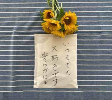 「いつまでも大好きです」と書かれた遺骨包みとひまわり｜海洋散骨の手続き｜清蓮