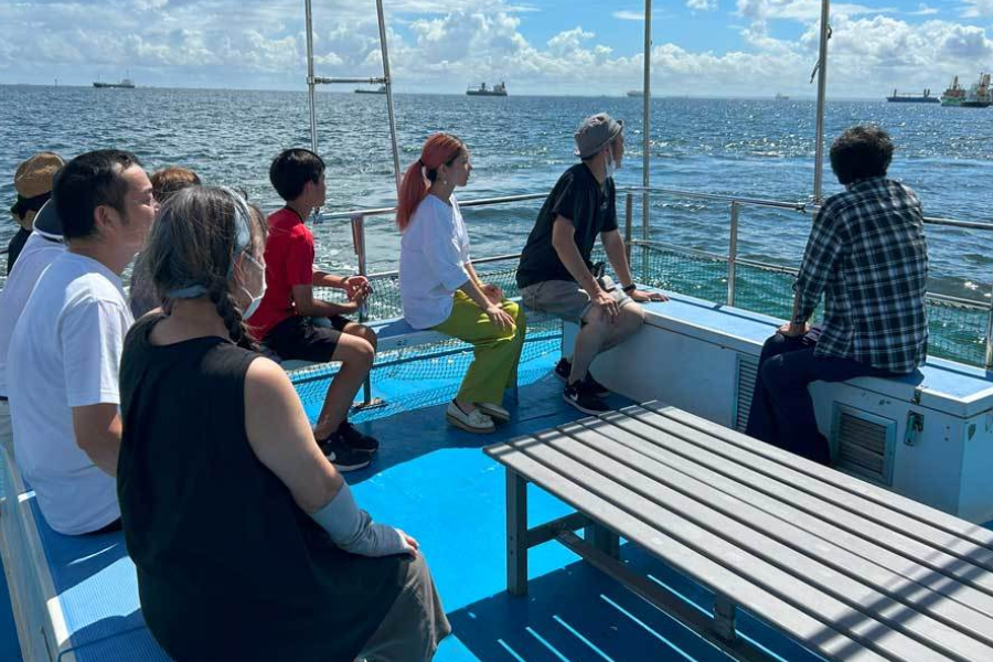 横浜の海。船上で穏やかな海を眺める6人の乗客たち。