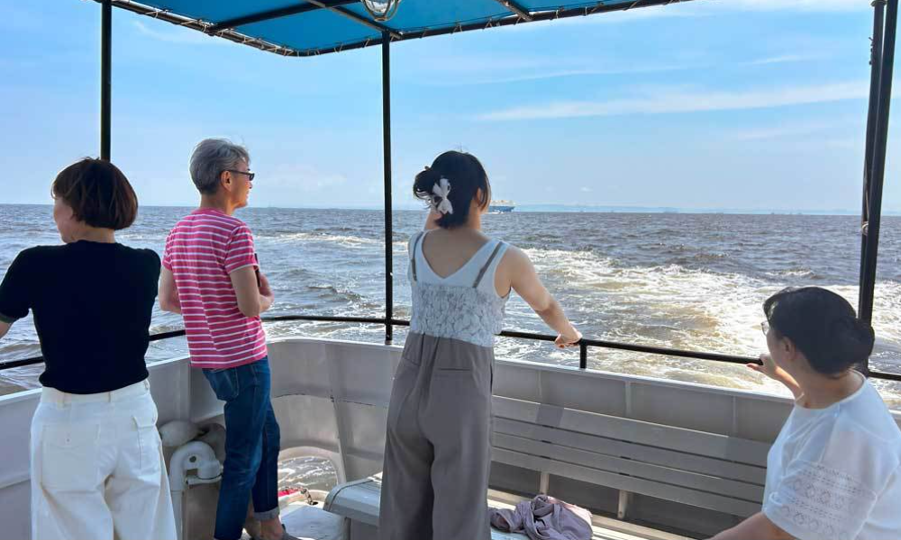 横浜ベイブリッジ沖の海を背景に、家族が静かに海を見つめて故人を偲ぶ散骨シーン