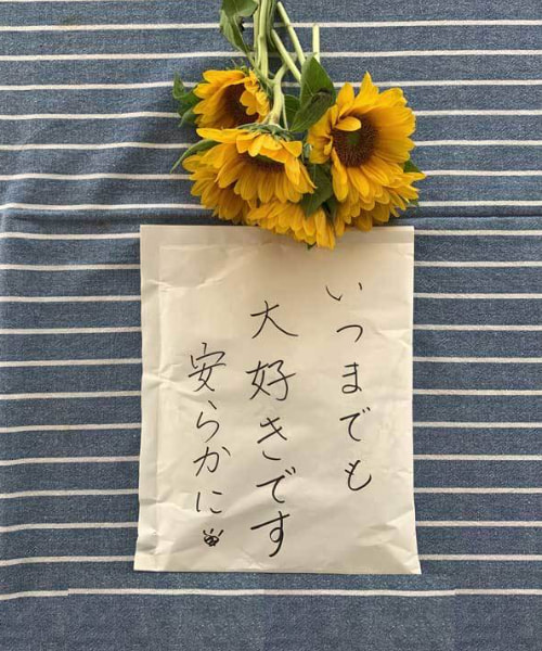 ひまわりの花束と「いつまでも大好きです 安らかに」と書かれたお手紙