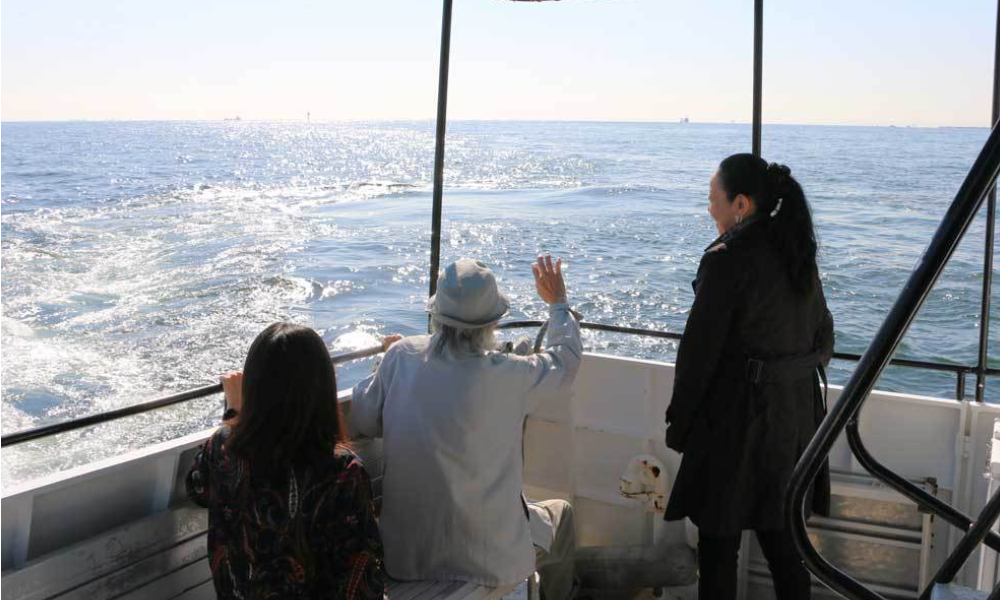 横浜のプライベート散骨で、船上から海へ手を振りながら故人を見送るご家族の後ろ姿