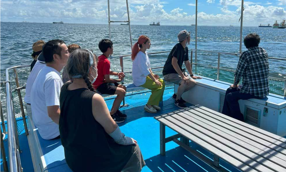 横浜のプライベート散骨で、船上から海へ手を振りながら故人を見送るご家族の後ろ姿