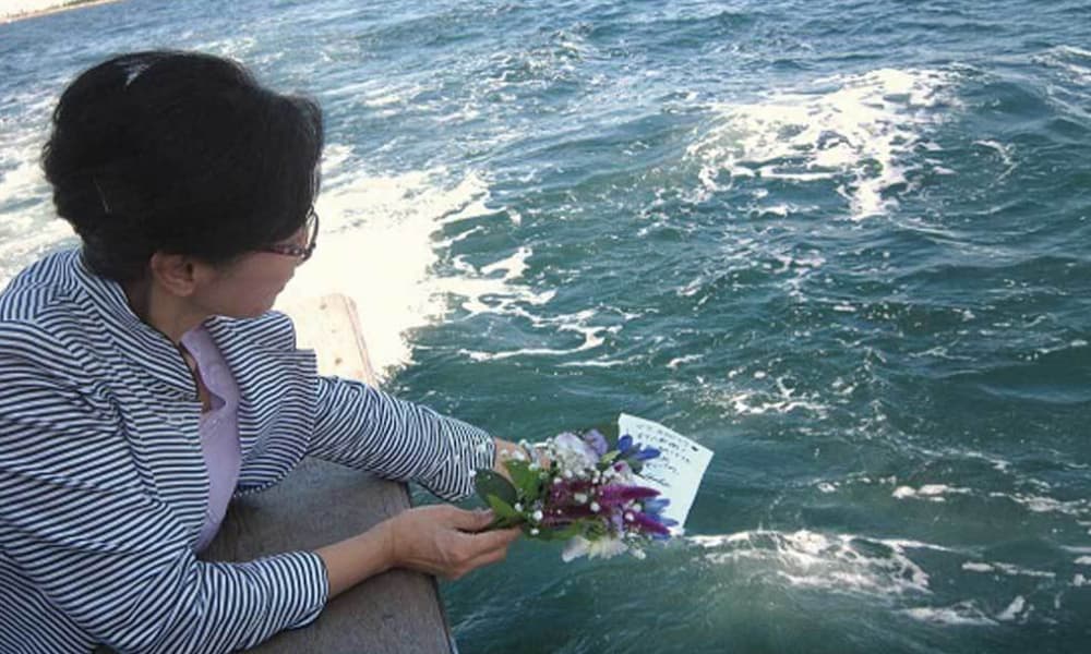 海洋散骨で花を手向けながら故人を見送るご家族