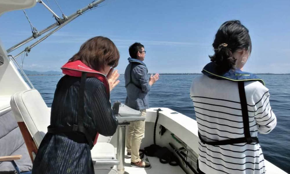 合同散骨で、ご家族が船上から故人を見送っている海洋散骨の様子