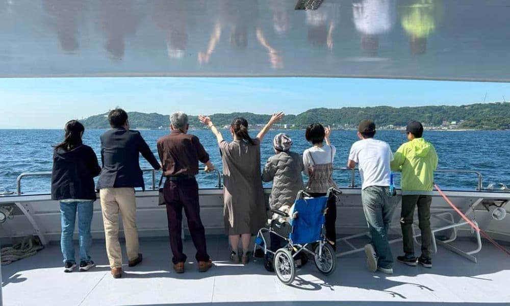 横須賀の海で行う海洋散骨。貸切の観光船デッキから、ご家族が車椅子の方とともに穏やかな海へ手を振り見送る様子