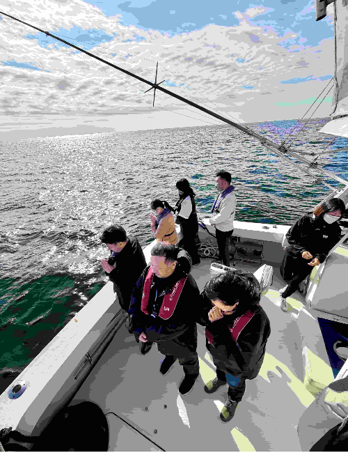 江ノ島沖の合同散骨で、ご家族が手を合わせてお別れをする様子。相模湾の海上にて。