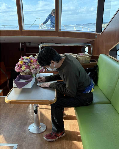 海洋散骨に向けて船内でメッセージを書くご家族の様子