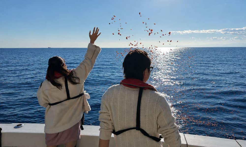 海洋散骨で海へ花びらを手向けながら故人を想うご家族
