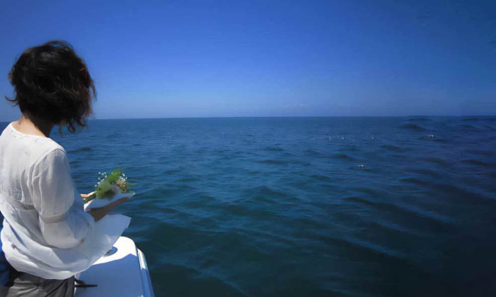 海を見つめながら花を手にする海洋散骨当日の様子